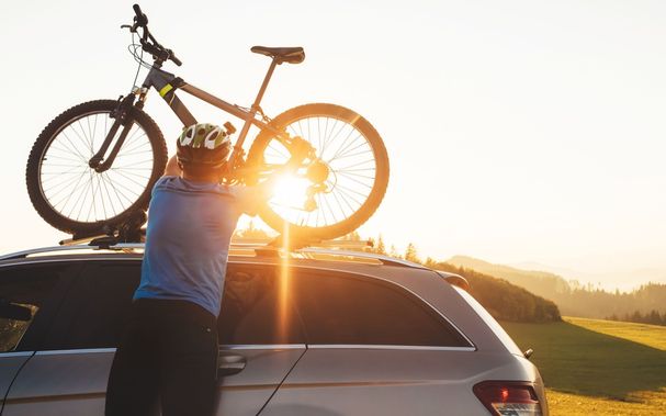 Fahrer-in-Radkleidung-und-Schutzhelm-installiert-sein-Fahrrad-auf-dem-Autodach