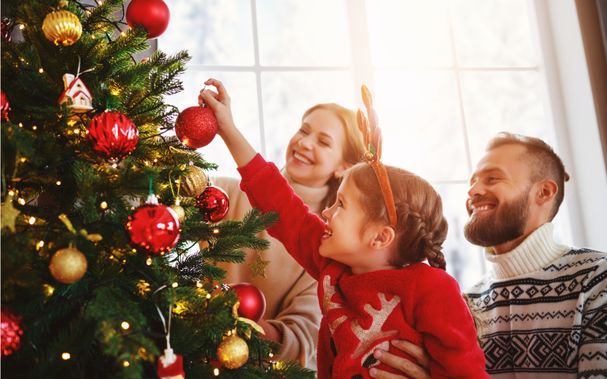 Famile-schückt-weihnachtsbaum-mit-lichterkette