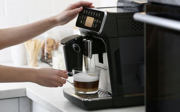 Frau-die-moderne-Espressomaschine-verwendet-um-Kaffee-mit-Milch