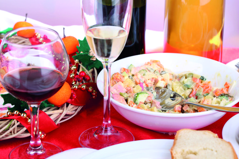 silvesterschmaus eindruck mit halbvollem rotweinglas einem champagnerglas und heringsschmaus in einem teller neben adventkranz