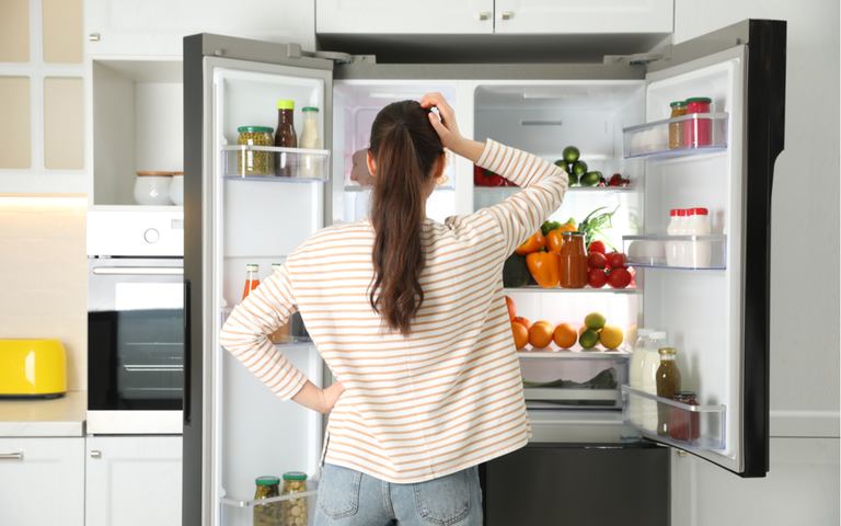 Junge Frau in der Nähe von offenem Kühlschrank in der Küche, Draufsicht.png