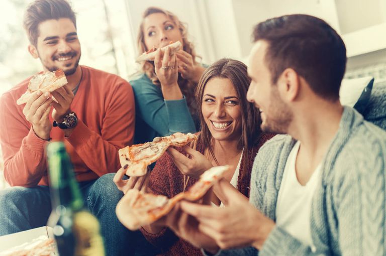 menschen sitzen beieinander und genießen pizza