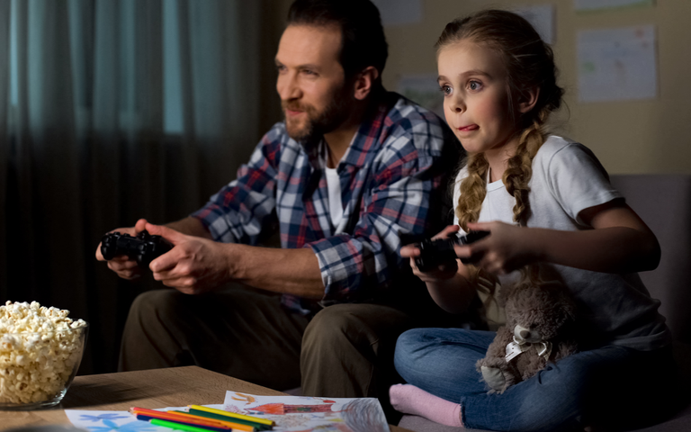 Tochter und Vater spielen Videospiele im Wohnzimmer.png