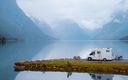Wohnmobil parkt am Ufer eines idilischen Sees mit Bergen im Hintergrund.jpg