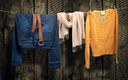 blaue jeans brauner gürtel beiger schal und ocker pullover hängen auf einer wäscheleine vor hölzernem hintergrund