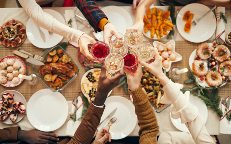 Menschen, die beim festlichem Dinner-Tisch bei Weihnachtsfeiern mit Freunden und Familie anstoßen