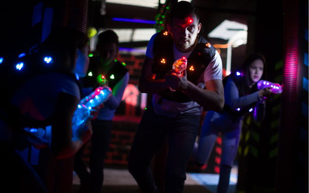 Junge Männer amüsieren sich mit Laserpostole in dunkle Lasertag Arena