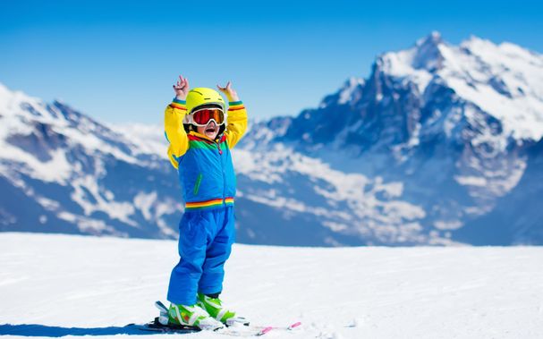 skiurlaub_kinder_winter_Kind mit gelben Helm_ski