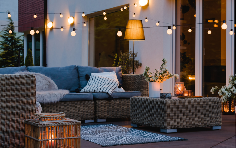 Sommerabend auf der Terrasse des schönen Vorstadthauses mit Lichtern im Garten