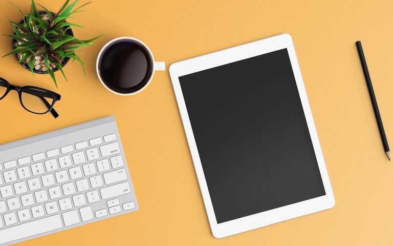 tablet-mit-tastatur-kaffee-und-pflanze-auf-orangen-hintergrund