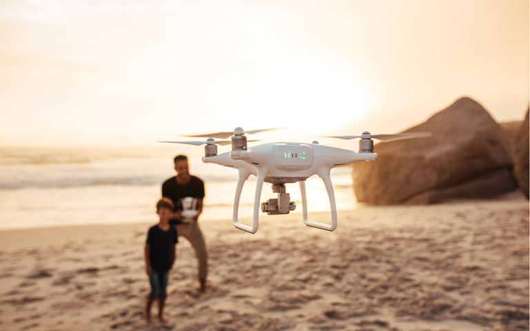 Vater und Sohn am Strand fliegen eine Drohne